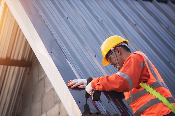 Man working on building shows the durable benefits of metal roof installation