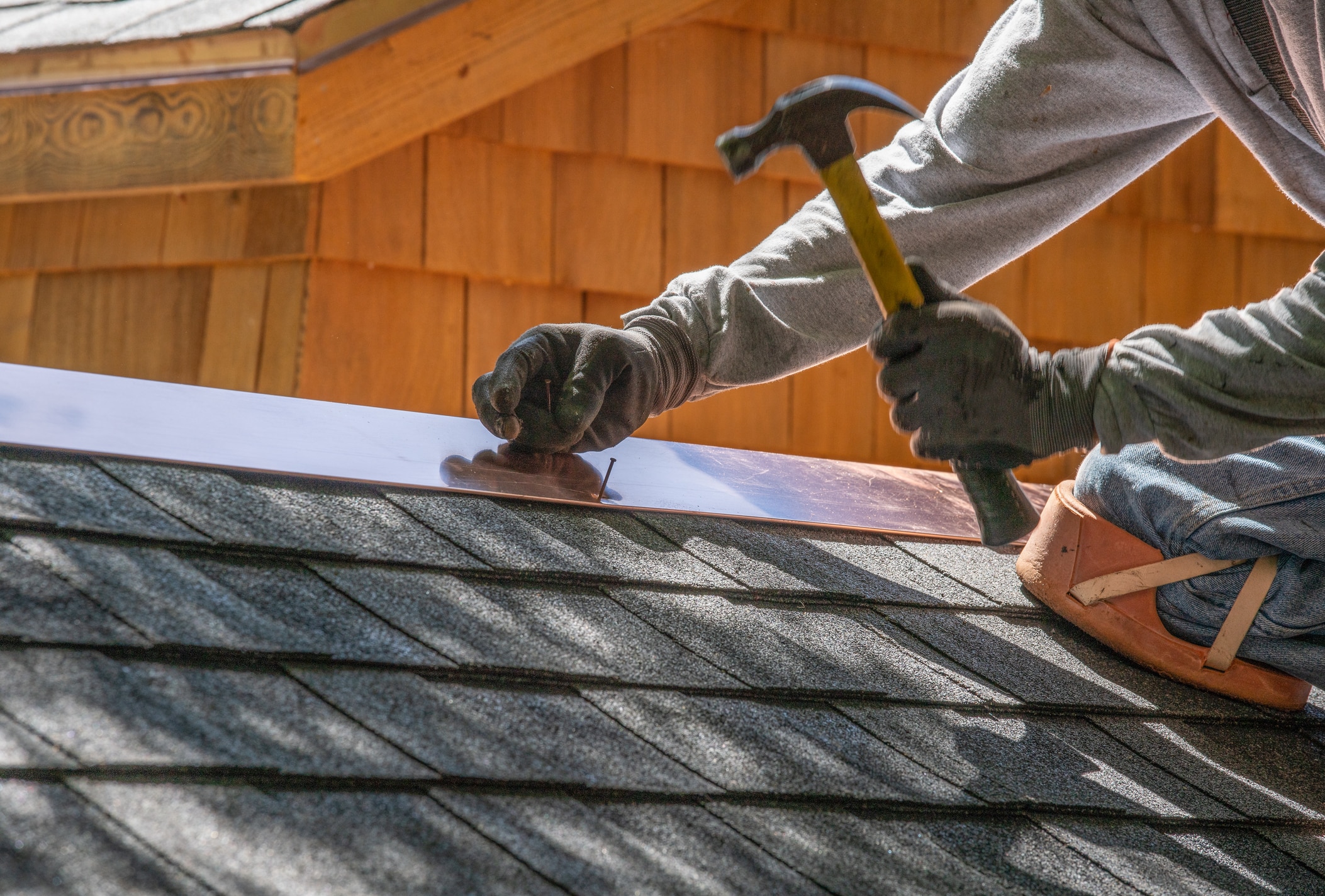 Contractor with a hammer and nails demonstrating the question: Can You Install a Metal Roof Over Shingles?