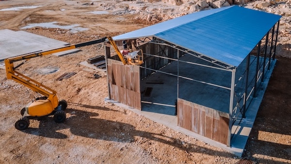 A scenic construction site featuring pole barns covington residents choose - framed warehouses with blue roofs, blending industrial design and coastal beauty