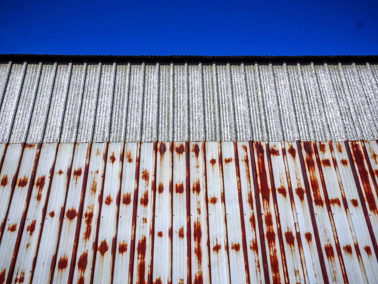 Roof shows half metal roof rust and half roofing in perfect condition